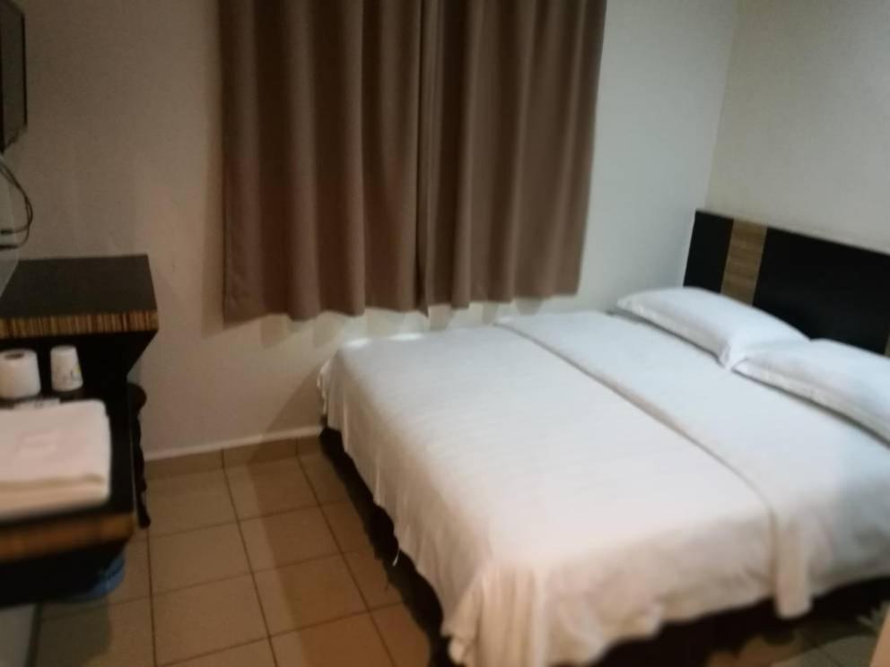 a hotel room with two beds and a desk at Hotel Traveller in Kota Kinabalu