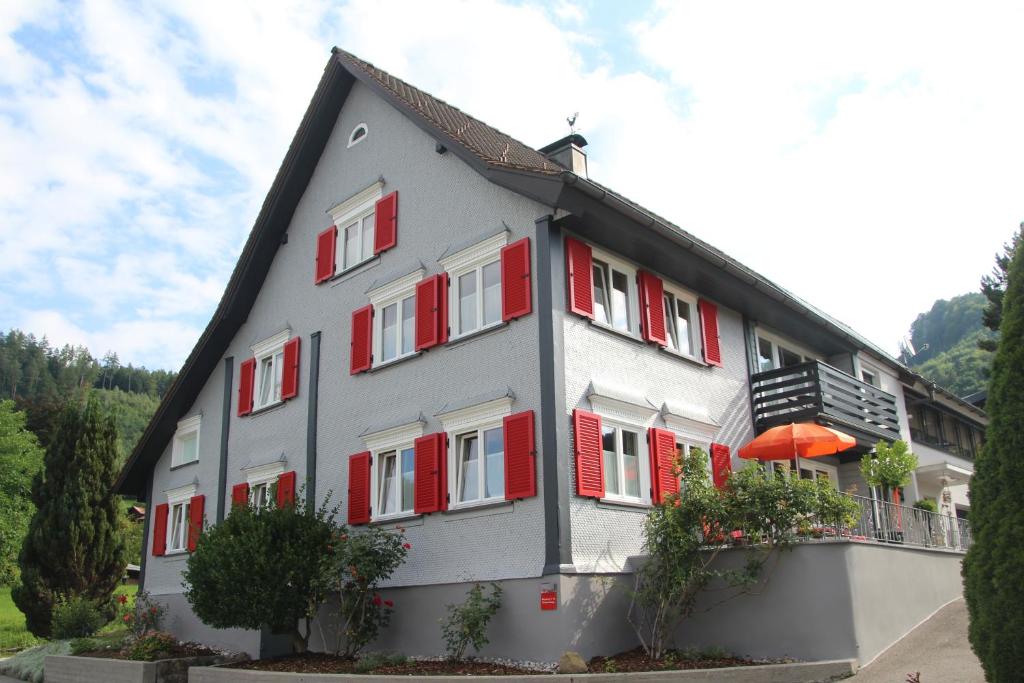 Gästehaus Mangold Fritsch في Klaus: مبنى رمادي وبه مصاريع حمراء