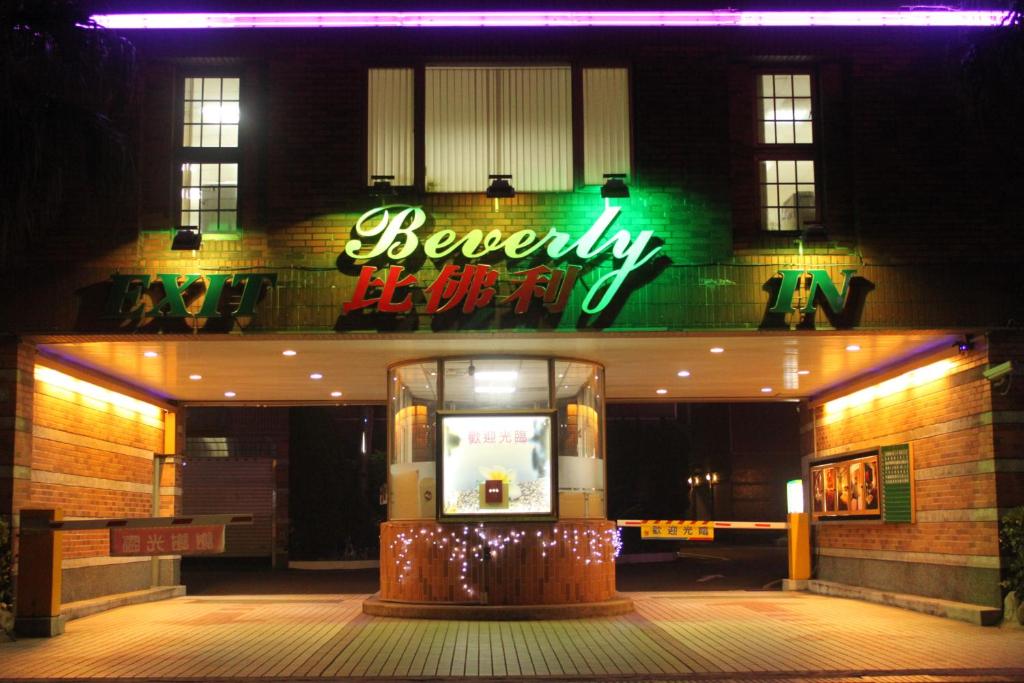 a building with a neon sign in front of it at Beverly Commercial Motel in Luzhu