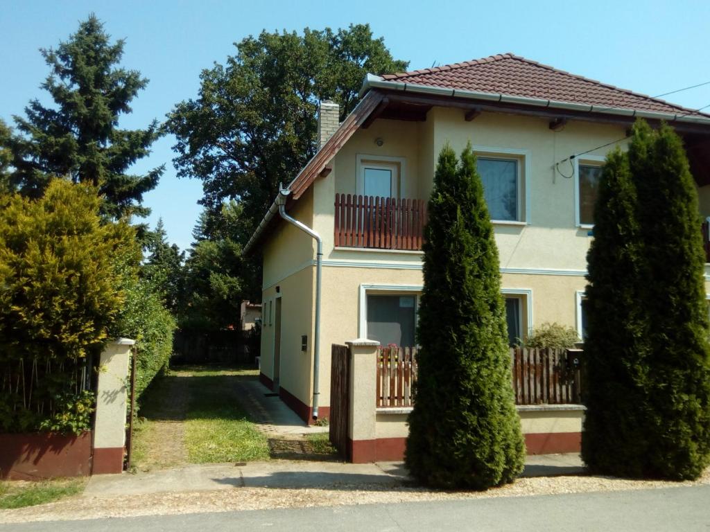 a house with a fence and two trees at Éva vendégház Guesthouse in Hajdúszoboszló