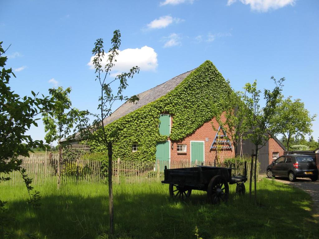 een huis bedekt met klimop met een vrachtwagen ervoor bij 't Zwaluwennest in Exloo