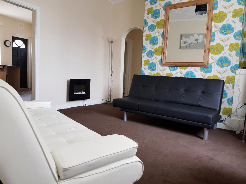 a living room with a black couch and a mirror at Blackpoolholidaylets Vicarage Lane in Blackpool