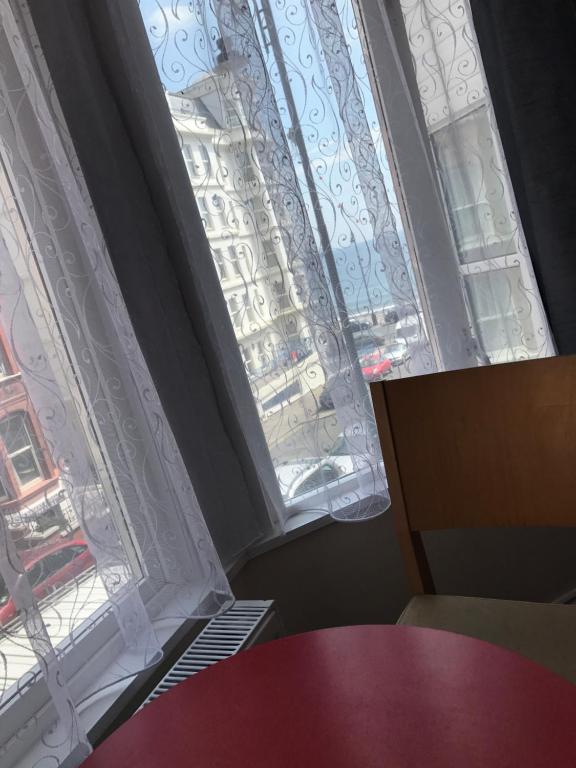 two windows with white curtains and a red table at Glenfaba Guest House in Douglas