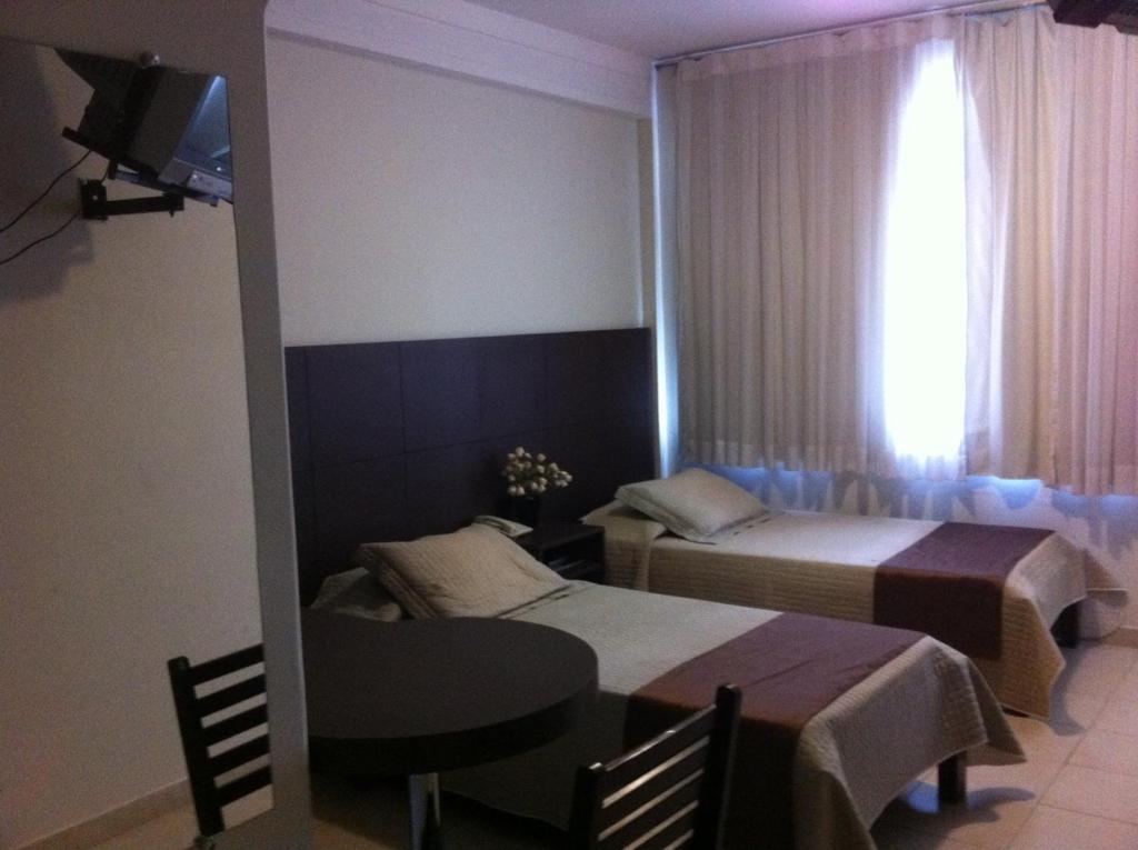 um quarto com 2 camas, uma mesa e uma janela em Palace Hotel em Itajubá