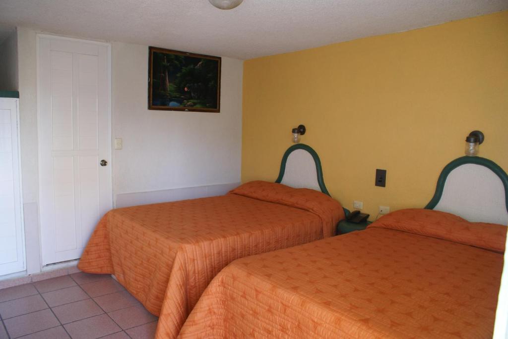 2 camas en una habitación con sábanas de color naranja en Hotel del Angel, en Catemaco