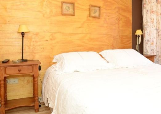 a bedroom with a white bed and a wooden wall at Encomenderos Suites - Apartamentos Amoblados in Santiago