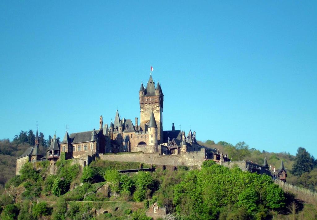 um castelo no topo de uma colina com uma torre de relógio em Ferienwohnung Burgenblick em Cochem