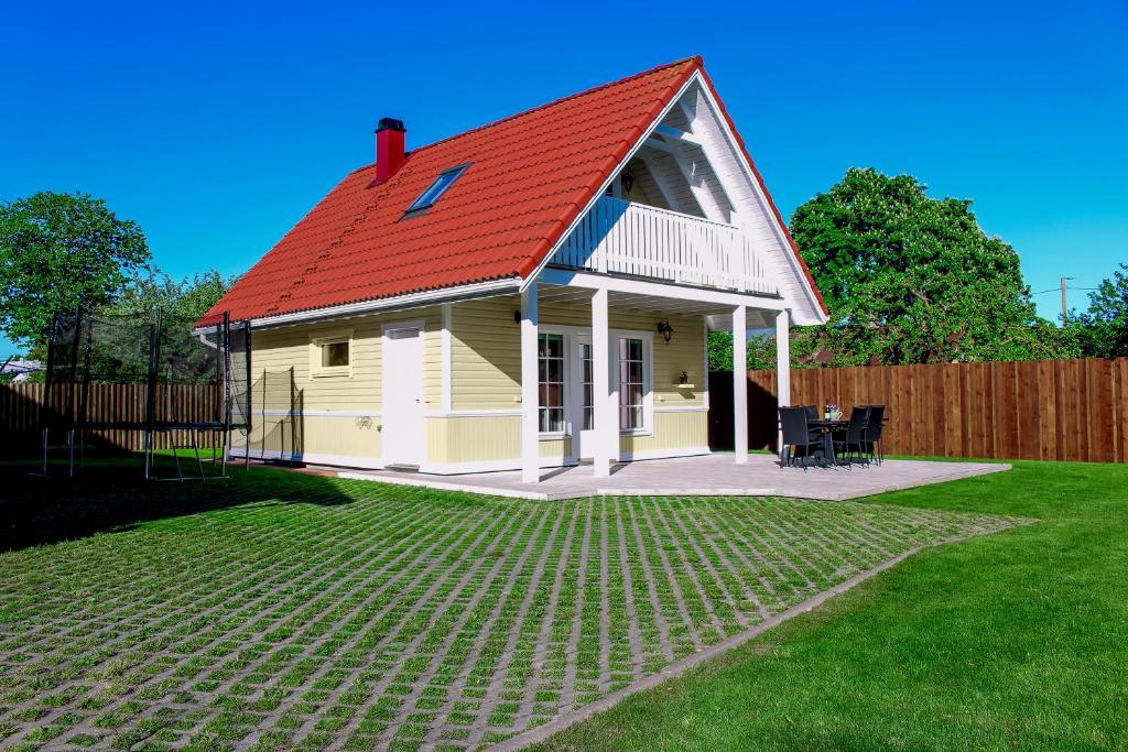 a small house with a red roof on a yard at Kasekese Holiday Home with Sauna and Garden in Kuressaare