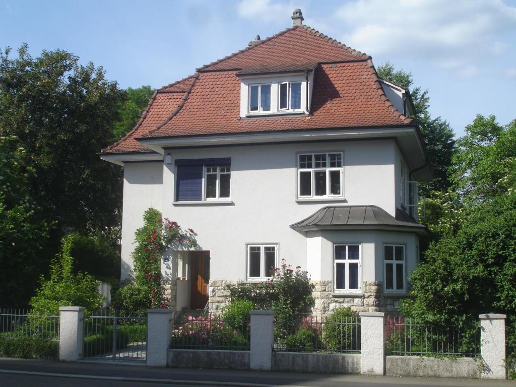 Biały dom z czerwonym dachem w obiekcie Villa Am Rosenfelspark w mieście Lörrach