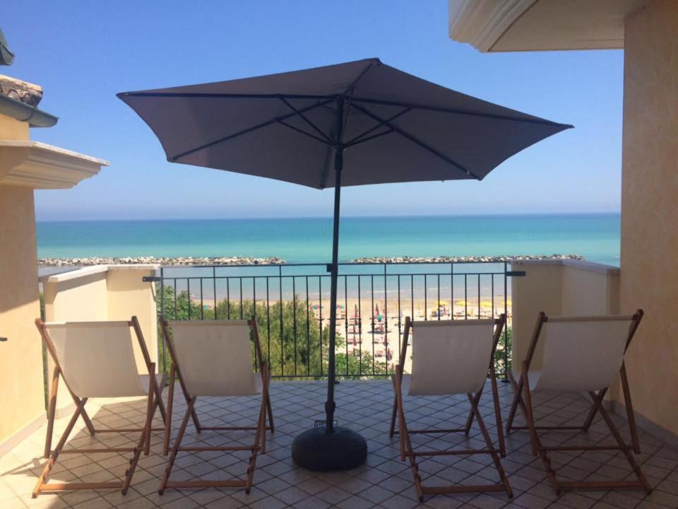 patio z 2 krzesłami i parasolem w obiekcie Hotel Capital w mieście Cupra Marittima