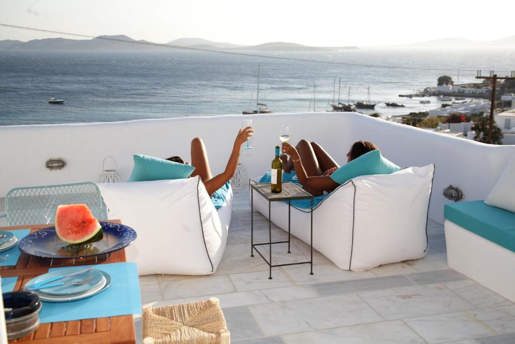a woman laying on a balcony with a bottle of wine at Mykonos Moussa in Agios Ioannis Mykonos