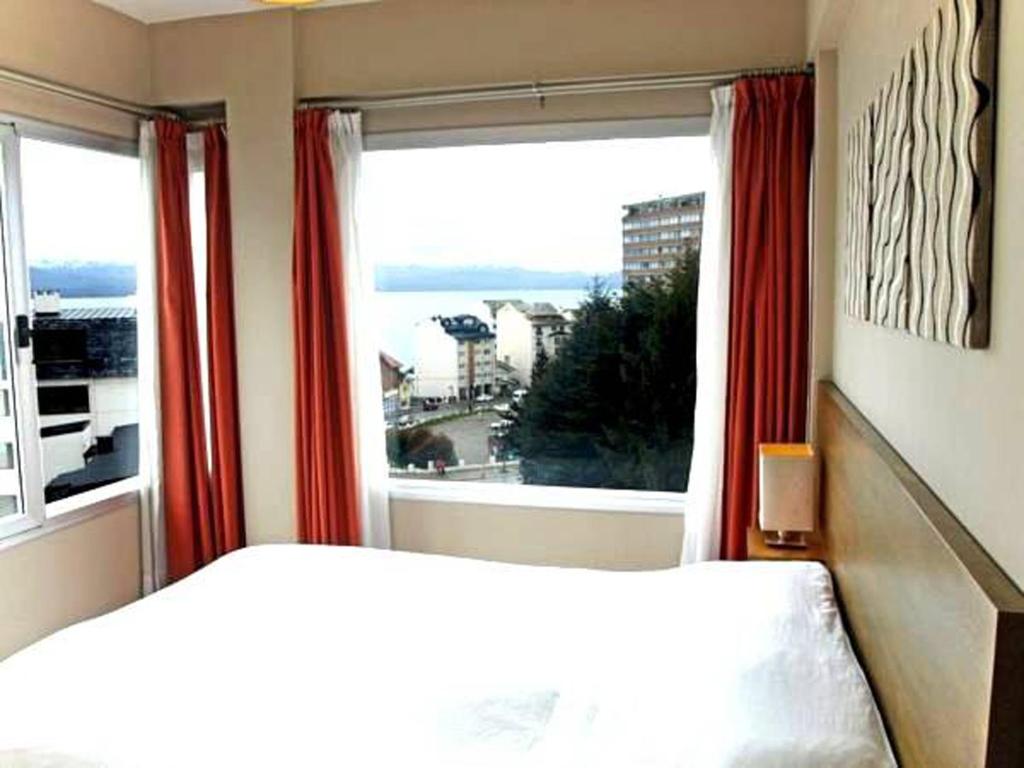 a bedroom with a bed and a large window at BarilocheCentro I in San Carlos de Bariloche