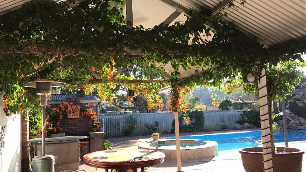 a pergola with a table and a swimming pool at Swan Valley Rest Cottage in Middle Swan