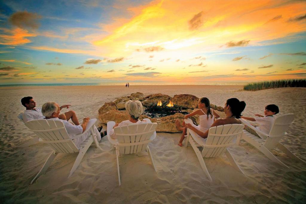 a group of people sitting around a campfire on the beach at Luxury 5 Star Condominium Water Front 3 Beds 2 Bath Pool Hot-Tub Beach And City Views in Clearwater Beach