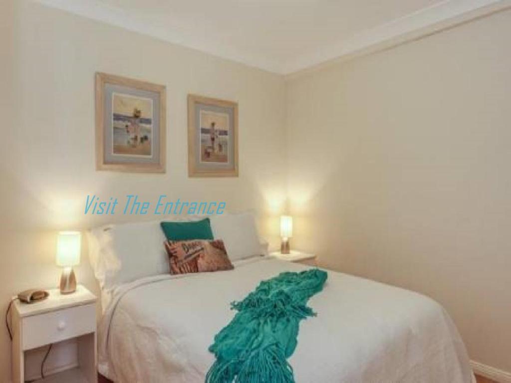 a bedroom with a bed with a green dress on it at Ocean Pines Apartments 4 in The Entrance