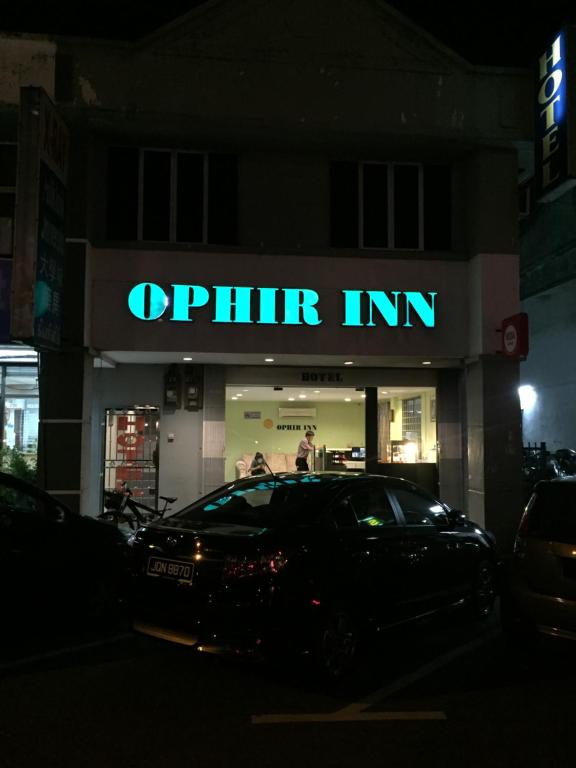 un'auto parcheggiata di fronte a un negozio di notte di Ophir Inn a Skudai