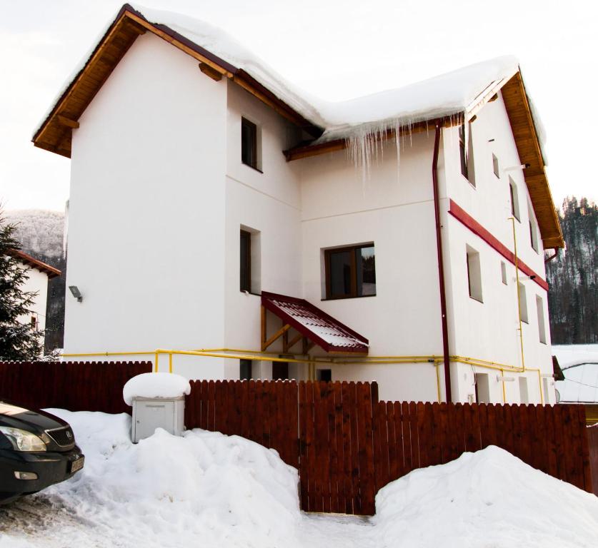 a house covered in snow next to a fence at Vila Alma Azuga in Azuga