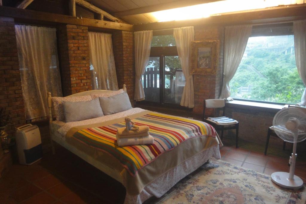 1 dormitorio con 1 cama en una habitación con ventanas en Jiufen Aromatherapy B&B, en Jiufen