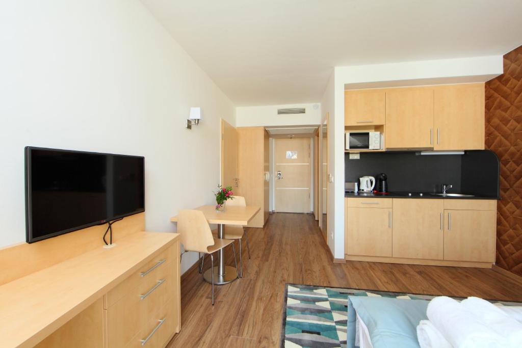 バラトンフレドにあるHoliday Exclusive Apartman Balatonfüredのリビングルーム(薄型テレビ付)、キッチンが備わります。