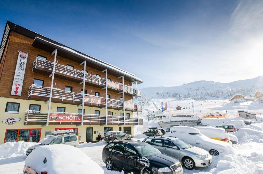 Ferienwohnung Ski-Hans في Planneralm: موقف سيارات مغطى بالثلج أمام مبنى