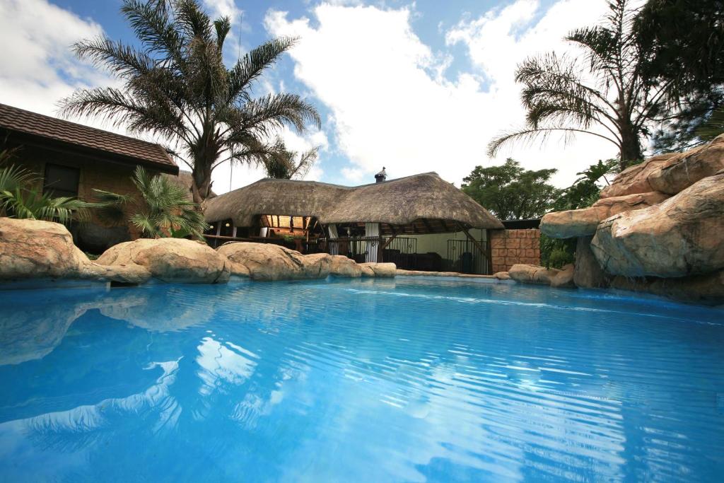 a large swimming pool with a house in the background at Summer Garden Guest House (The Palms) in Benoni