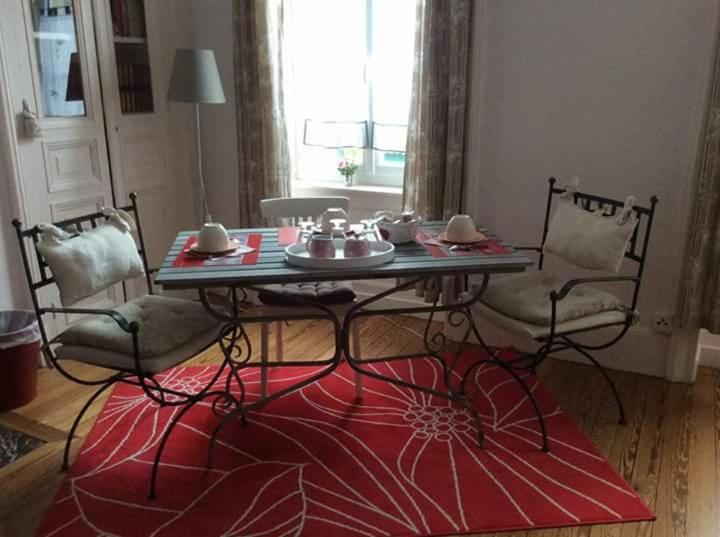 mesa y sillas en una habitación con alfombra roja en la Tourelle en Normandie, en Saint-Pierre-Église