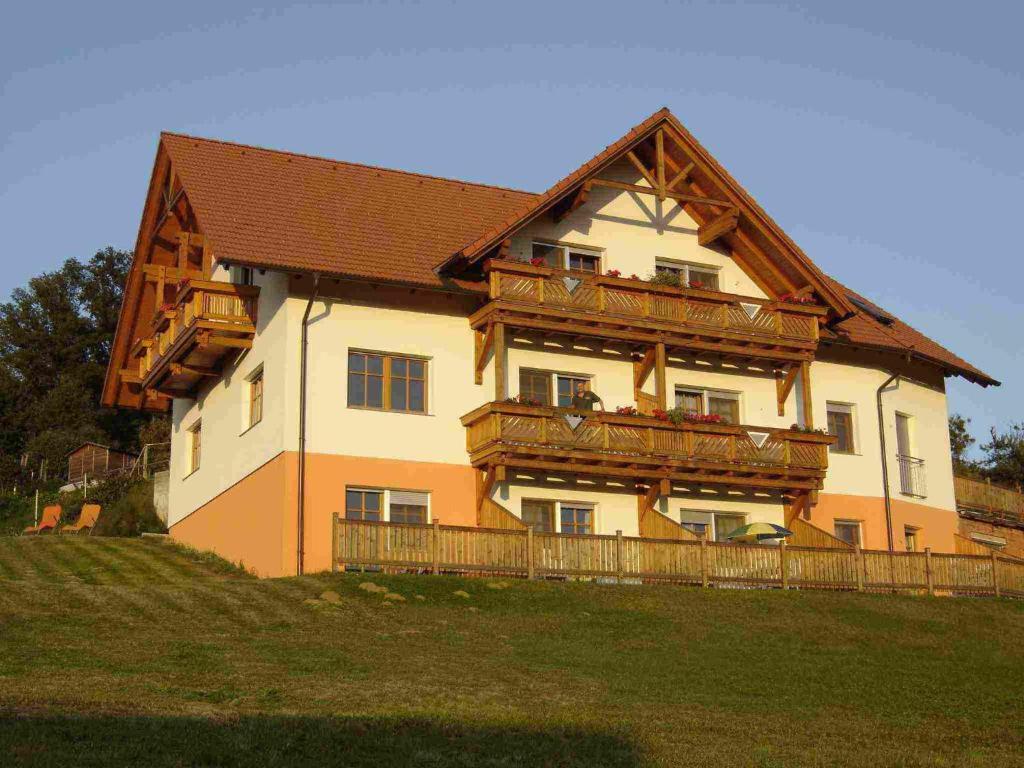 Cette grande maison dispose d'un balcon en bois sur le côté. dans l'établissement Pension Ritz, à Loipersdorf bei Fürstenfeld