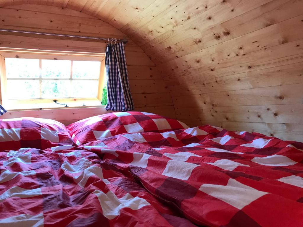 a bed with a red and white blanket in a room at Schlaffass - Schlafen im Holzfass in Tattendorf