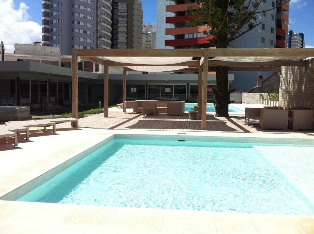 uma grande piscina com um pavilhão ao lado de um edifício em Forest Tower 2 - Apartamento 305 em Punta del Este