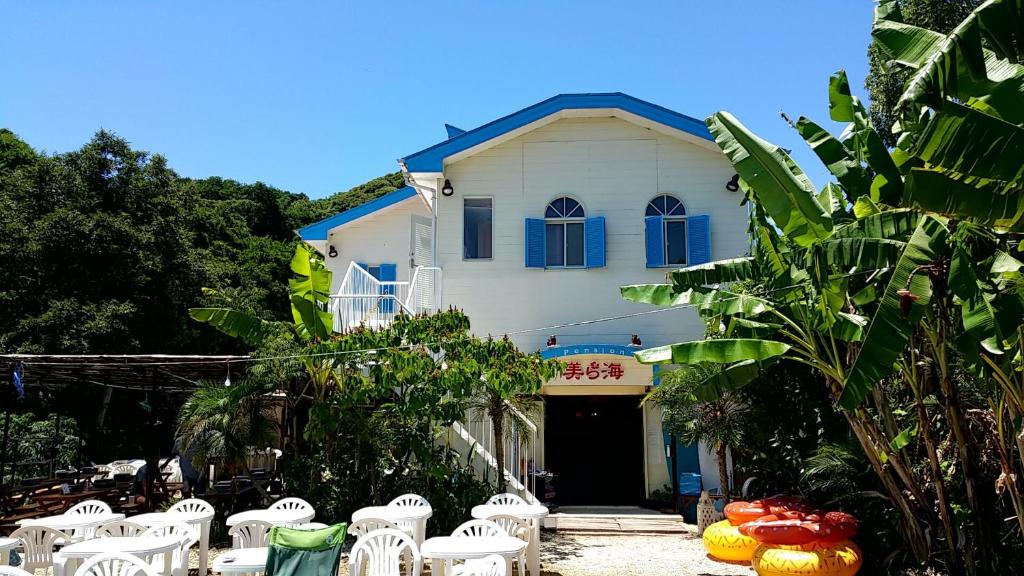 a white building with white chairs in front of it at Guest House Churaumi in Shimoda