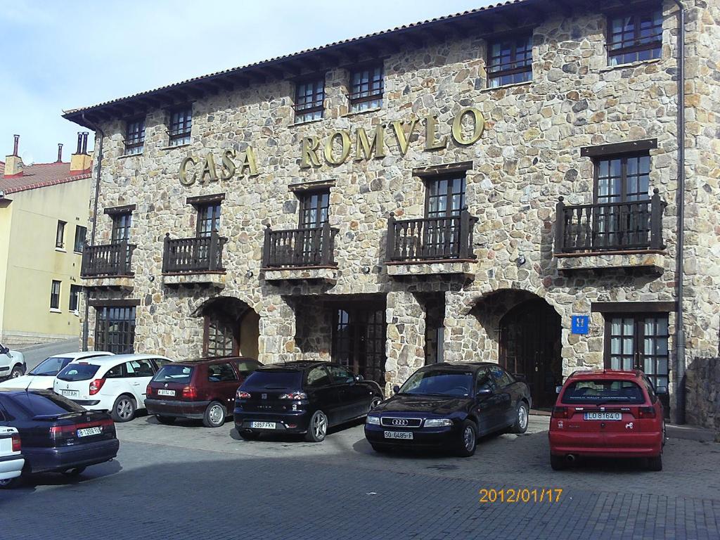 un edificio de piedra con coches estacionados frente a él en Casa Rómulo, en Duruelo de la Sierra
