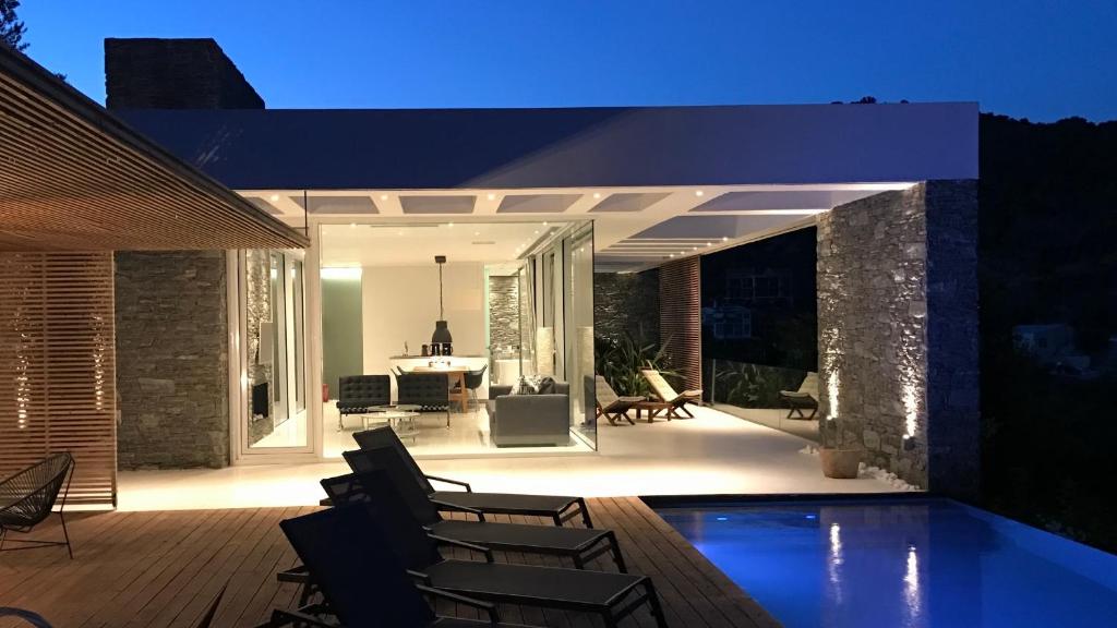 un patio con sillas y una piscina por la noche en A - Luxury Villas en Plomarion