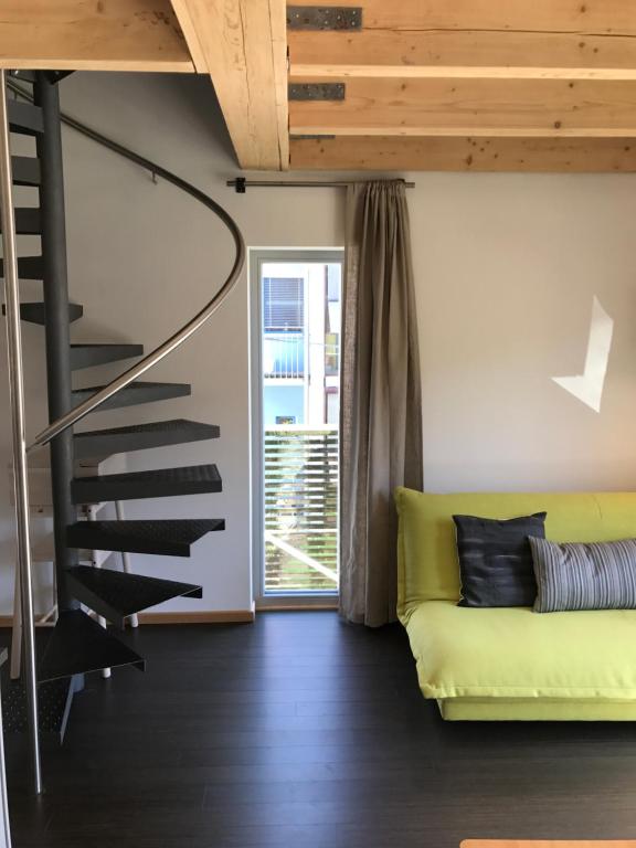 a living room with a yellow couch and a spiral staircase at Blackbird´s Nest in Wiesenbronn