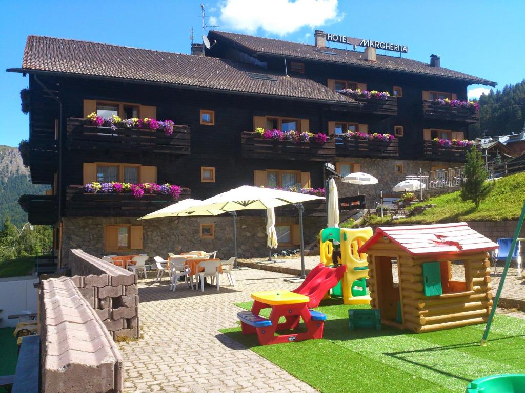 ein Gebäude mit einem Spielplatz vor einem Haus in der Unterkunft Hotel Margherita in Livigno