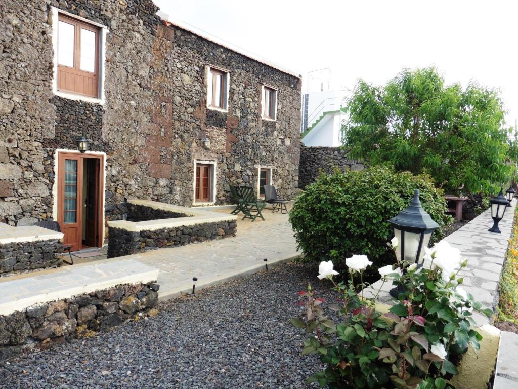 ein Backsteingebäude mit einem Innenhof mit Blumen davor in der Unterkunft Casa Rural Los Perales in Mocanal