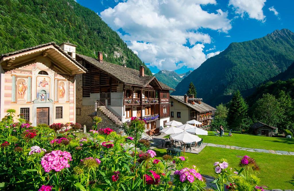 a building with flowers in front of a mountain at Albergo Montagna Di Luce in Alagna Valsesia