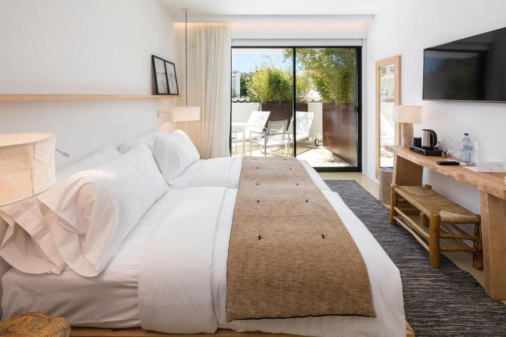 a bedroom with a large white bed and a balcony at Lagos Avenida Hotel in Lagos