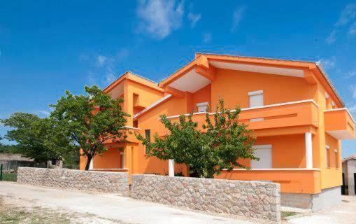 um edifício laranja com árvores em frente em Apartments Kalac em Posedarje