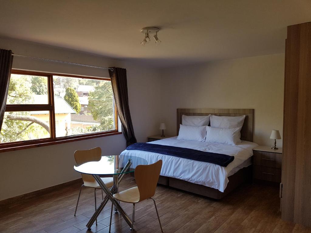 sypialnia z łóżkiem, stołem i oknem w obiekcie 50 Galena Affordable Luxury w mieście Roodepoort