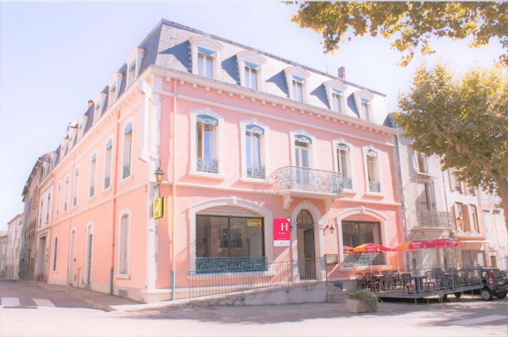 ein rosafarbenes Gebäude auf einer Straße mit einem Baum in der Unterkunft Hôtel De France in Chalabre