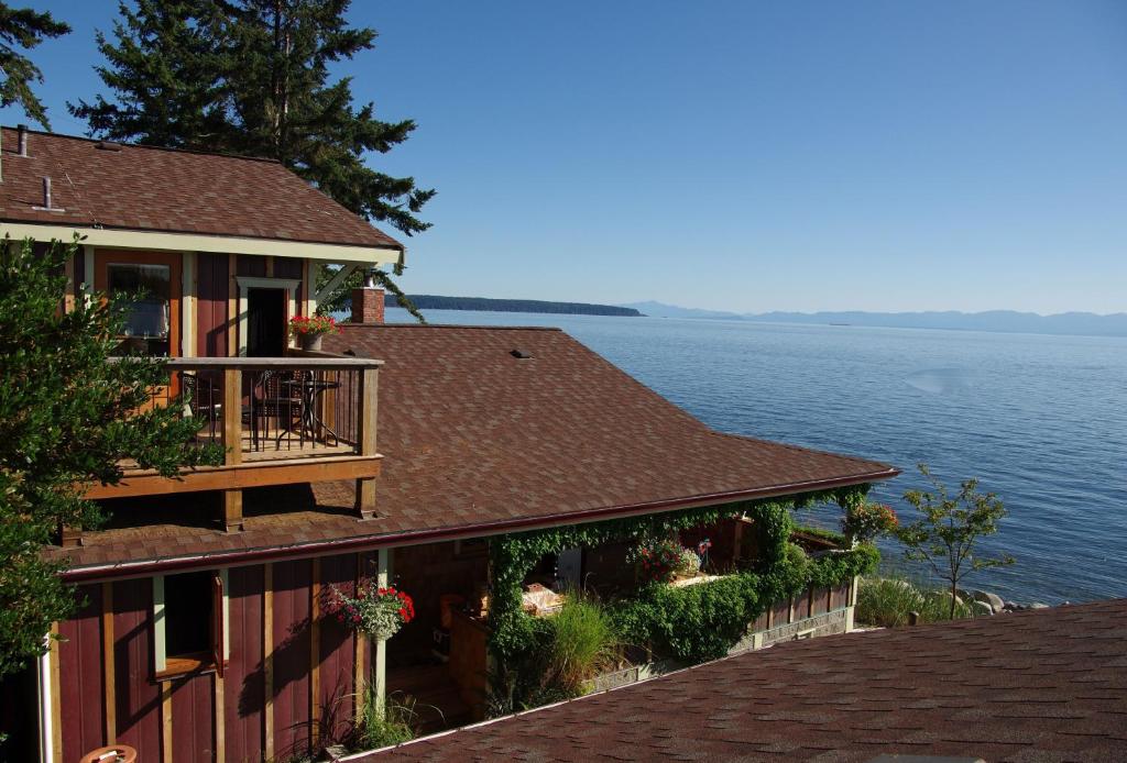 a building with a balcony next to the water at Blitz Beach House Oceanside Suite in Powell River