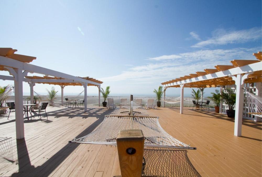 een houten terras met tafels en stoelen op het strand bij Aqua Beach Hotel in Wildwood Crest