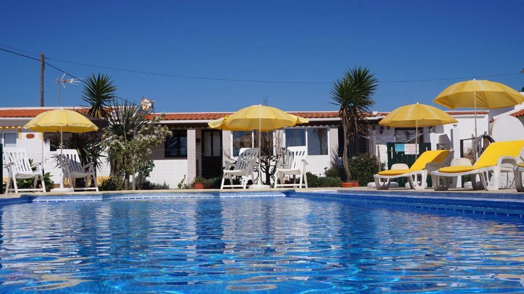 a swimming pool with chairs and umbrellas at Apartamentos na Quinta Altavista do Carvalhal in Zambujeira do Mar