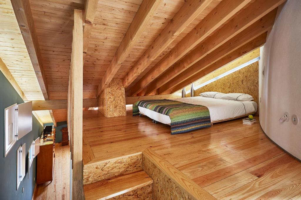 Ce lit se trouve dans un dortoir doté d'un plafond en bois. dans l'établissement Fence Houses, à Coimbra