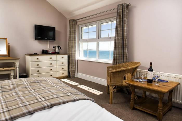 a bedroom with a bed and a table and a window at The Ship Hotel in Aberdaron