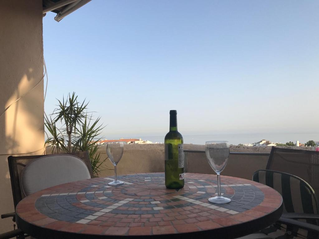 una botella de vino sentada en una mesa con dos copas de vino en Riviera Del Sol Penthouse, en Mijas Costa