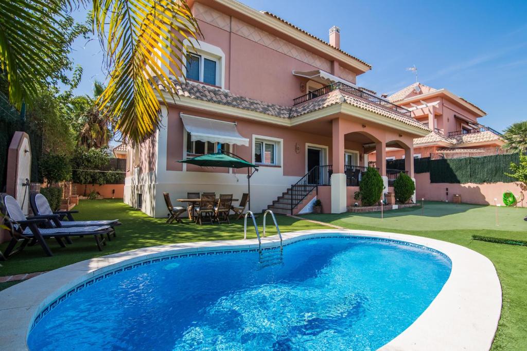 a villa with a swimming pool in front of a house at Benalmádena Coast Villa in Arroyo de la Miel