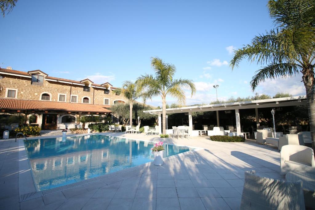 una piscina del resort con sedie e palme e un edificio di GaiaChiara Resort a Caserta