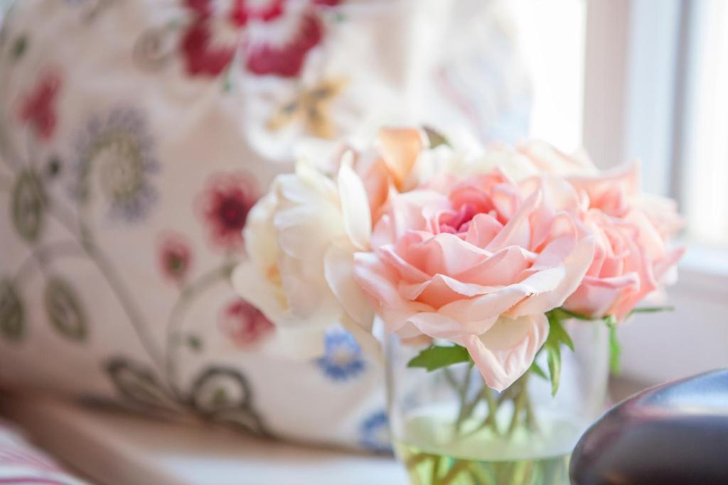 a vase filled with pink roses on a table at Hotel am Markt in Hungen