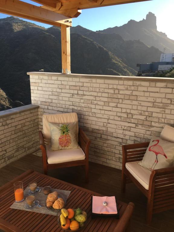 eine Terrasse mit 2 Stühlen und einem Tisch mit Obst darauf in der Unterkunft Casa Maeva in Tejeda